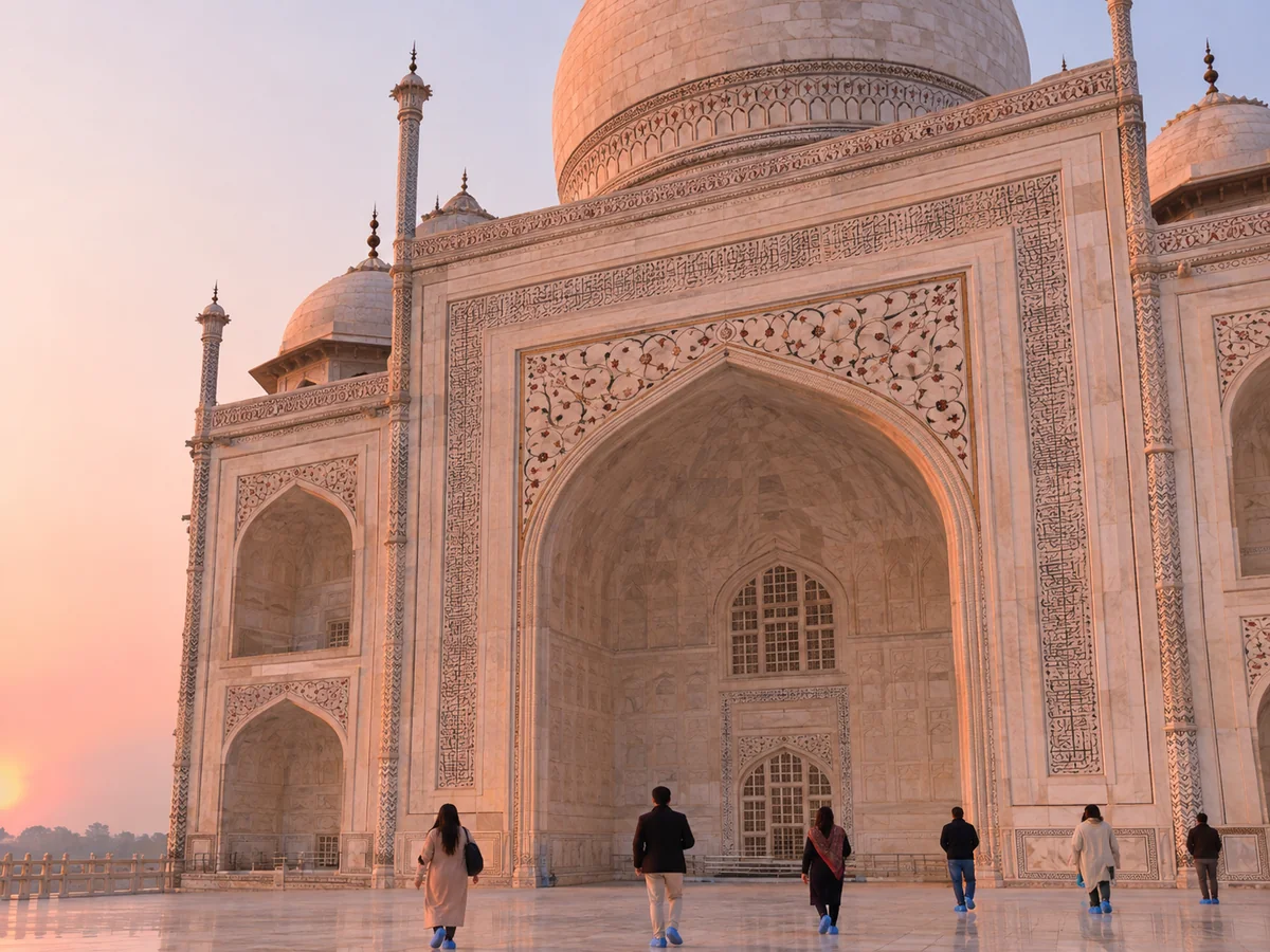 Das Mausoleum des Taj Mahal im sanften rosa Licht des Sonnenaufgangs mit Besuchern auf der Marmorplattform
